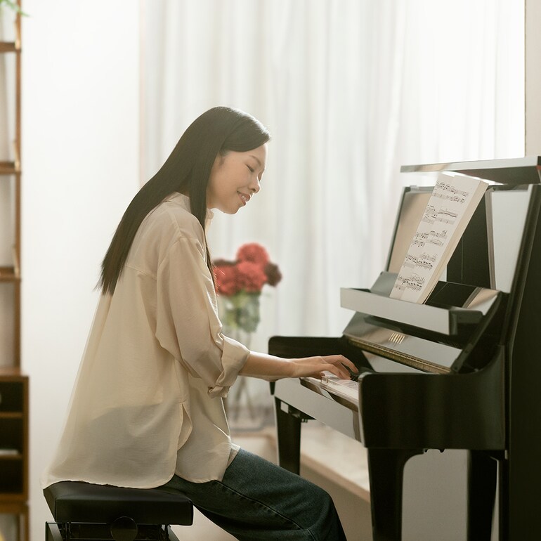 A woman enjoys playing the upright piano B series