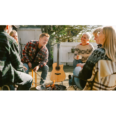 Group of friends outdoors with the TAG3 C acoustic guitar beside them.