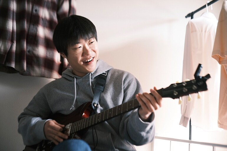 A man trying to play the guitar for the first time