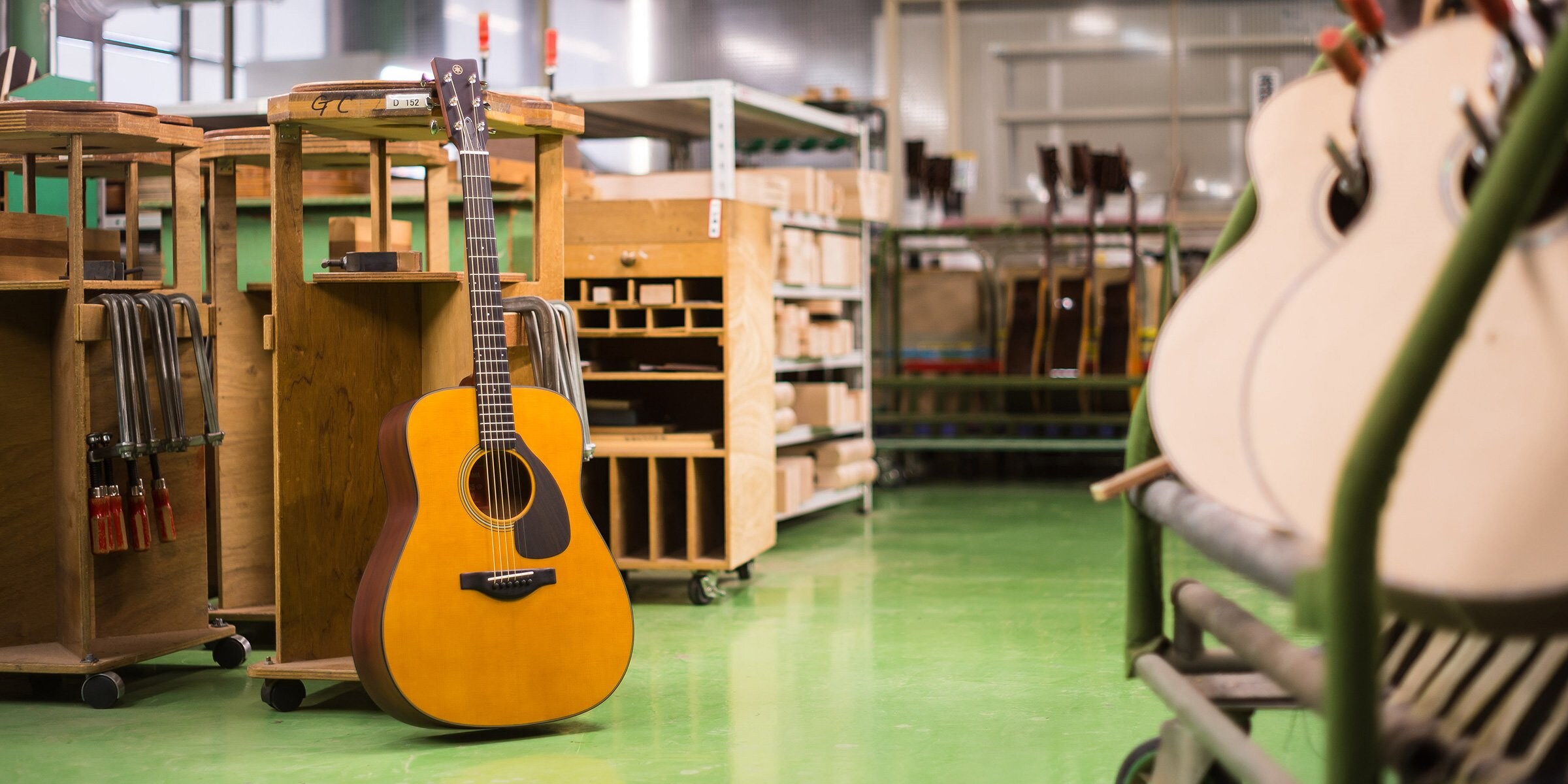 An FG5 guitar facing front leans against the workbench in the custom shop.