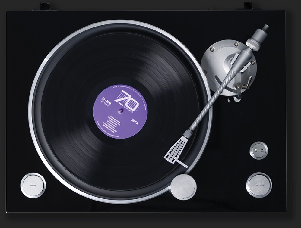 A top down view of a vinyl turntable with a record with a purple lable that reads Yamaha 70 Years of Hi-Fi